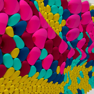 A close-up of a colorful textured surface made of overlapping teardrop-shaped elements in bright pink, cyan, yellow, blue, and magenta.