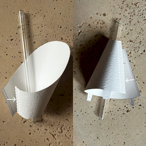 Paper folding technique for shaping a flat paper template into a curved cone using a round stick and soft pad for DIY geometric wall art.